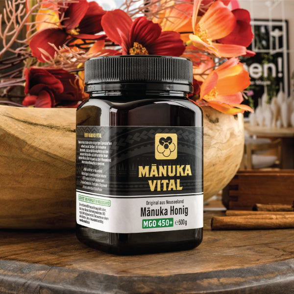 Manuka Honig MGO 450 von Manuka Vital – verschlossenes Glas auf Holztisch, im Hintergrund dekorative rote Blätter