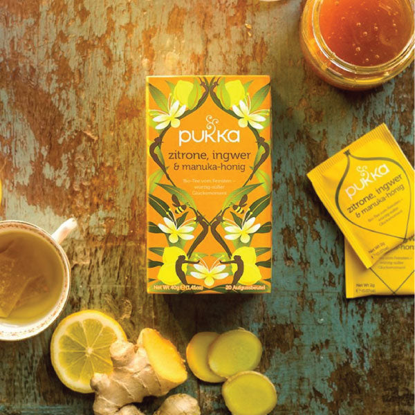 Pukka Manuka Honig Zitrone Ingwer Tee Verpackung mit heißem Tee auf dem Bild