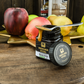 Offenes Glas Manuka Vital Honig mit einem Löffel voll Honig auf dem Glas und Obst im Hintergrund