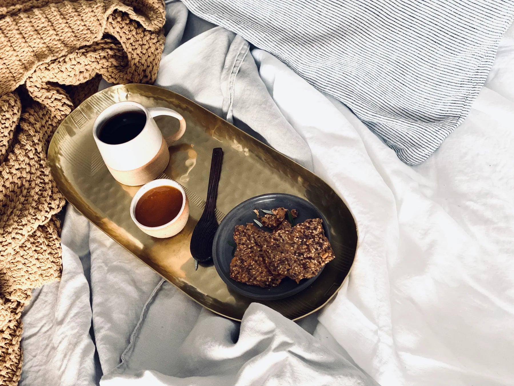 Eine Tasse Tee und ein Pot Manuka Honig steht auf einem Tablett auf dem Bett als Frühstück