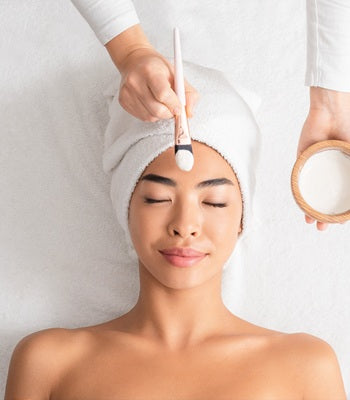 Eine Frau erhält von einer Kosmetikerin ein Peeling für das Gesicht