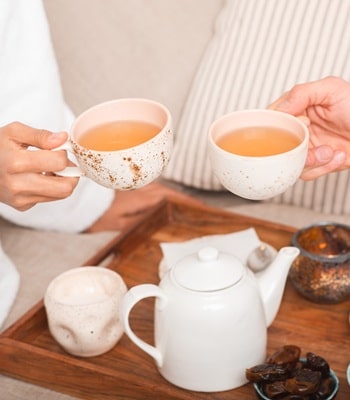 Zwei Personen halten eine Tasse frisch aufgebrühten Tee in der Hand